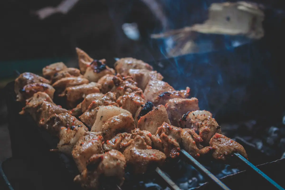 Carne assando sobre a brasa com fumaça subindo