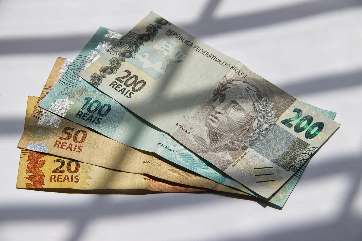 Notas de 20, 50, 100 e 200 reais abertas em leque sobre uma superfície clara