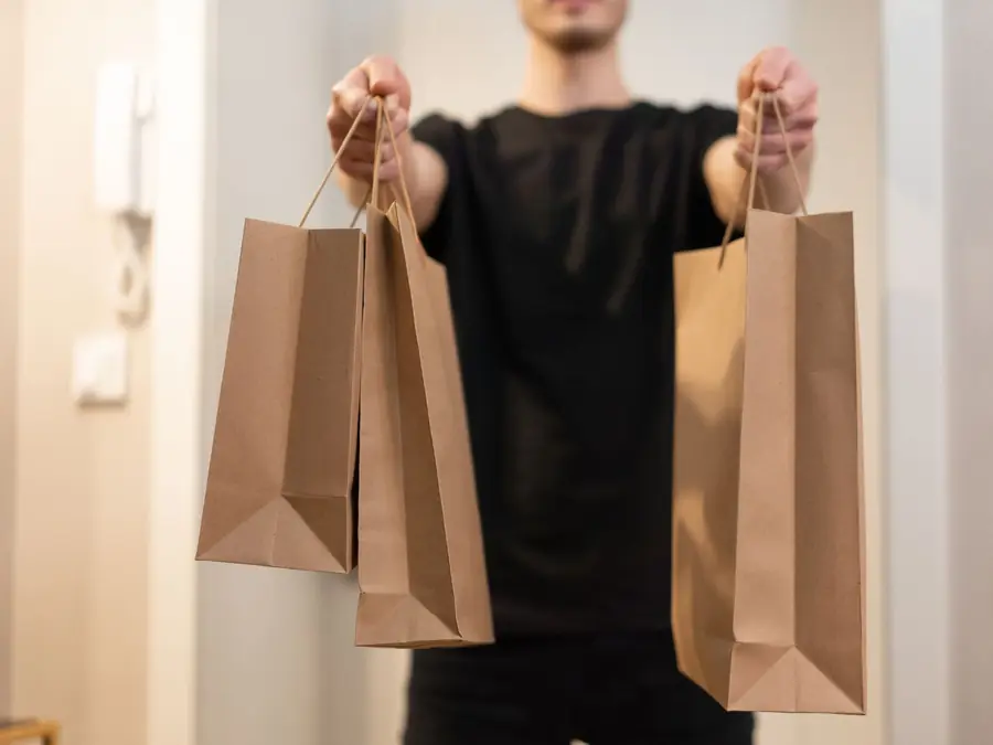 Pessoa segurando duas sacolas de papel com o pedido