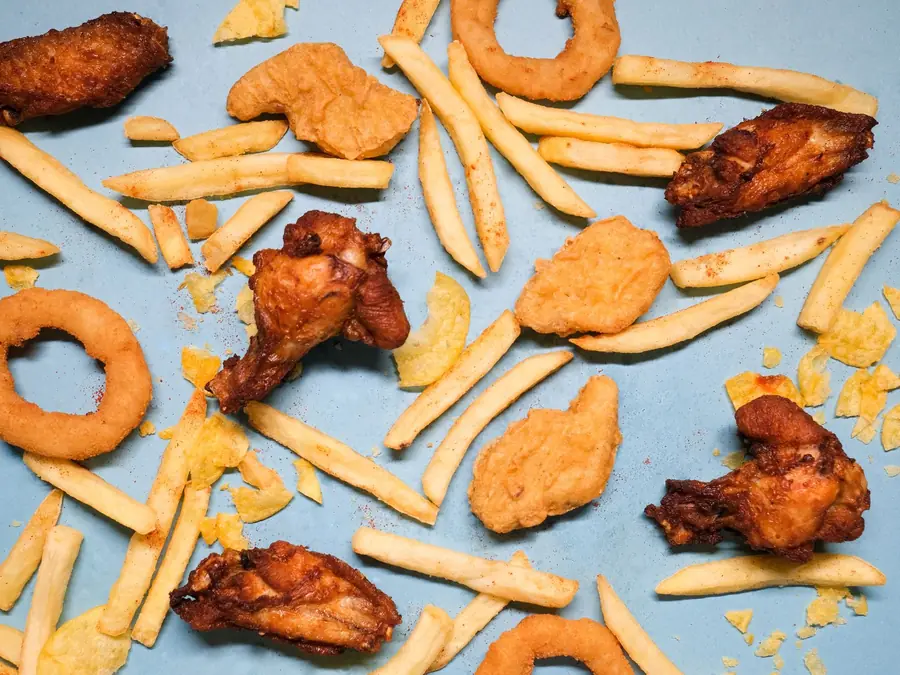 Porções de frango frito, batata e anéis de cebola vistos de cima